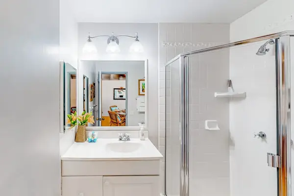 Bathroom includes glass shower, vanity, mirror, towels, and decorative accents