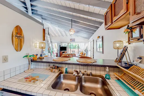 Kitchen sink area includes tiled counters, cabinets, window, and dishware