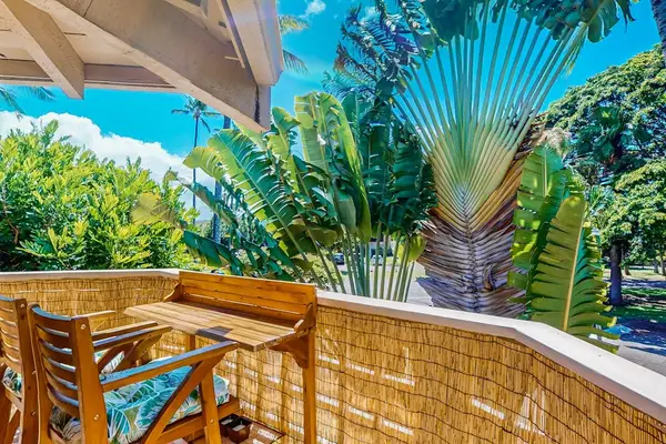 Balcony dining table sits beside tropical foliage and open-air views