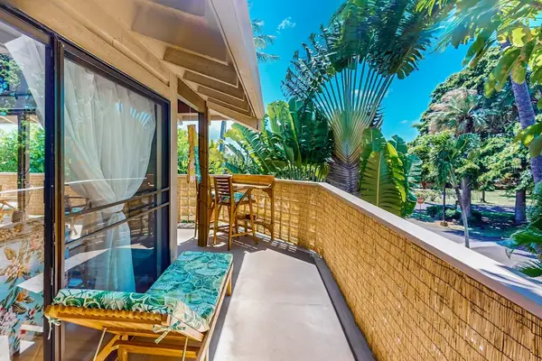 Balcony walkway features chair, sliding doors, tropical foliage, and railing