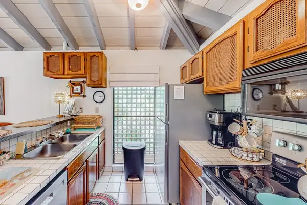 Kitchen showcases wood cabinetry, cooking appliances, counters, and bright windows
