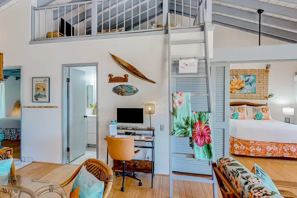 Living room entry displays colorful seating, doors, artwork, and plants