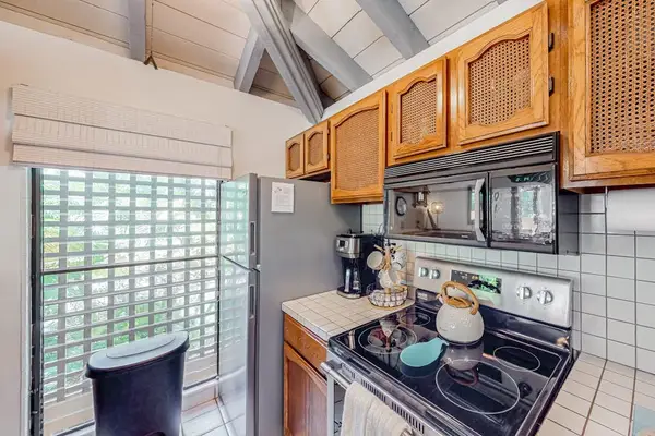 Kitchen corner includes stove, countertop, wood cabinets, window, and cookware