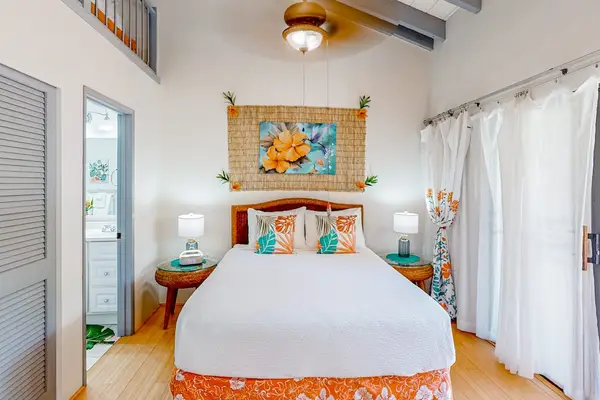 First bedroom features queen bed, artwork, ceiling fan, and curtains