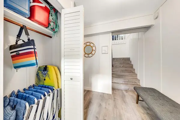 Storage keeps beach gear organized beside stairs and hallway