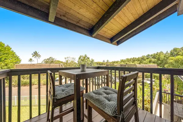 Shaded balcony seating overlooks tropical grounds beneath vaulted wooden eaves