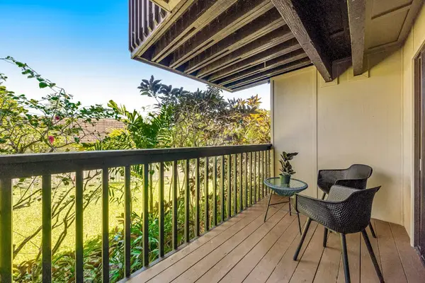 Quiet balcony chairs overlook leafy gardens beneath shaded tropical eaves