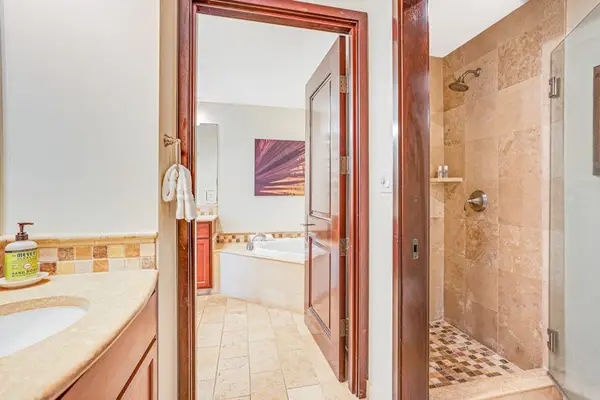 Luxurious secondary en suite featuring dual sinks, a large soaking garden tub, and a spacious tiled walk-in shower.