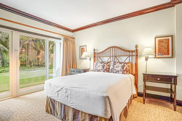 Comfortable guest bedroom with a queen bed, en suite bathroom, and sliding glass doors that fill the room with natural light and provide easy outdoor access.