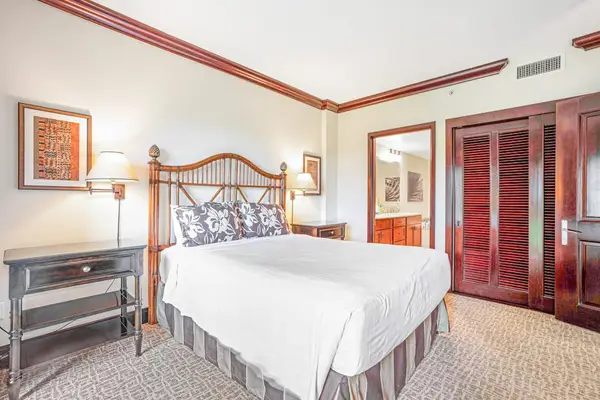 Comfortable guest bedroom with a queen bed, en suite bathroom, and sliding glass doors that fill the room with natural light and provide easy outdoor access.