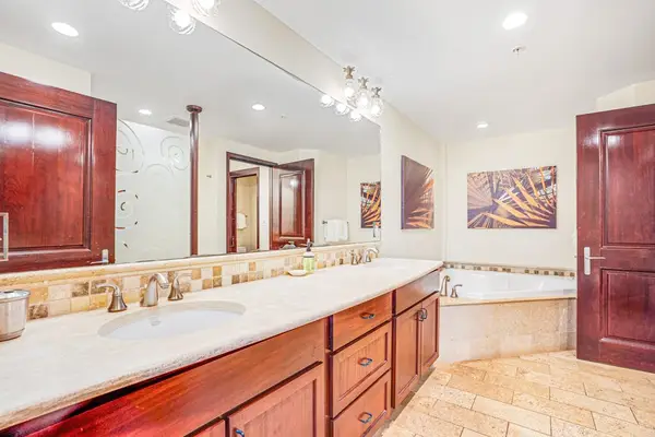 Luxurious secondary en suite featuring dual sinks, a large soaking garden tub, and a spacious tiled walk-in shower.