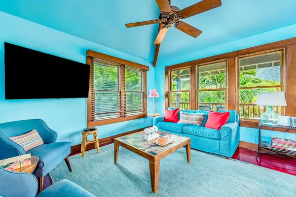 Sunlit living room features blue walls, comfortable sofas, and windows