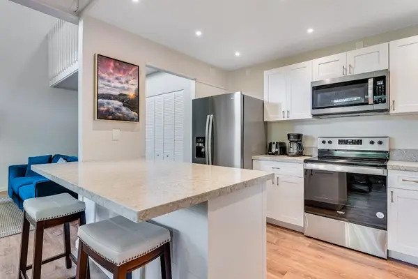 Modern open-concept kitchen with sleek stainless steel appliances and barstool seating—perfect for casual dining, gathering with guests, or keeping your sous chef close while you cook.