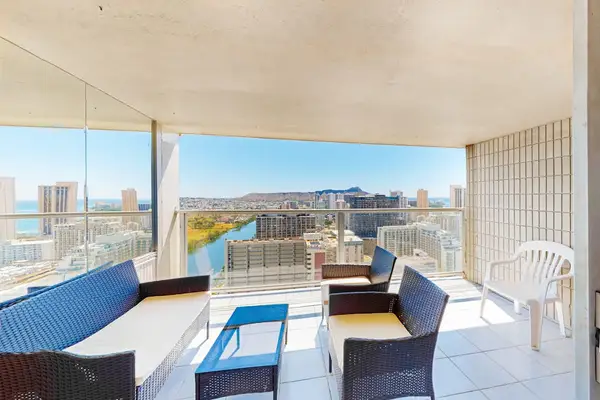 Covered balcony area featuring comfortable outdoor wicker seating, tile flooring, and direct views toward Diamond Head and the canal.