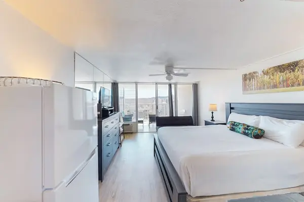 Bright studio floor plan with light flooring, a king bed setup, and floor-to-ceiling glass sliding doors opening to the balcony.