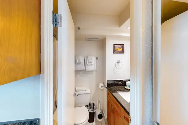 The private bathroom offers a functional design complete with a toilet, fresh towels, and a vanity area.
