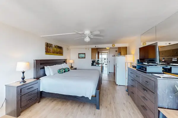 This open-concept studio offers a plush bed, ceiling fan, and flat-screen TV in a bright and inviting layout.