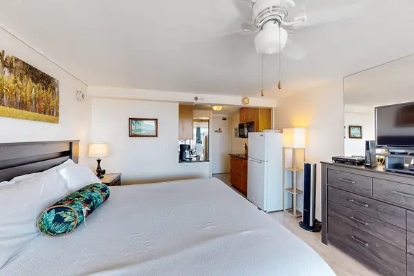 This studio layout seamlessly combines a comfortable sleeping area with a full dresser, flat-screen TV, and easy access to the kitchenette.