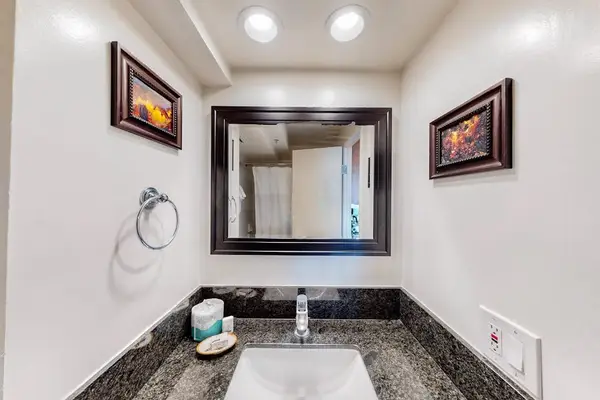 The bathroom vanity features a dark granite countertop, an undermount sink, a large framed mirror, and complimentary amenities.