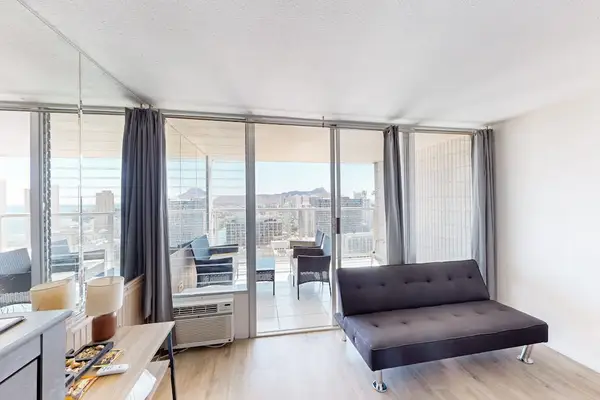 Convertible futon sofa positioned adjacent to floor-to-ceiling sliding glass doors, seamlessly blending indoor living with the private balcony.