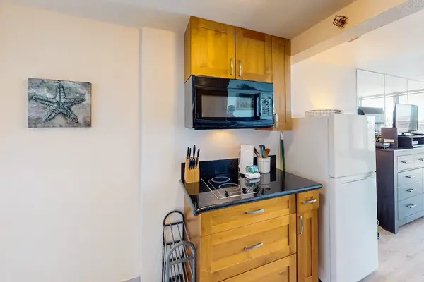 Built-in electric cooktop, microwave oven, custom wood cabinets, and full-size refrigerator. All ready for breakfast.