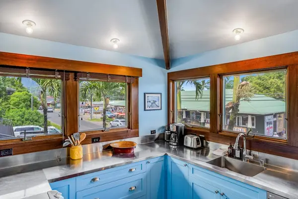 Open kitchen showcases practical counters, colorful stools, and tropical windows