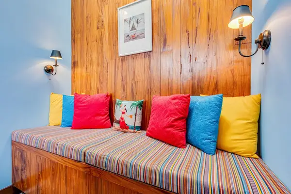 Window seat features striped upholstery, vibrant pillows, and wood paneling