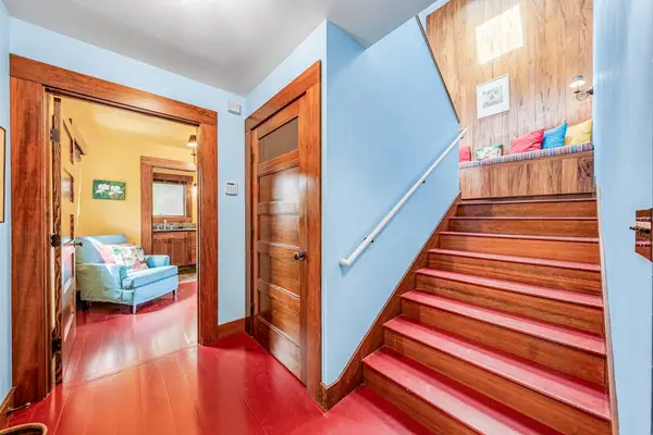 Wooden staircase leads upstairs beside walls and a bedroom entrance