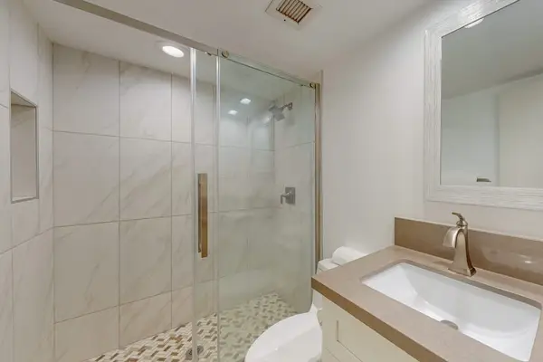 Guest bathroom with a spacious walk-in shower, vanity, and mirror for a comfortable and convenient stay