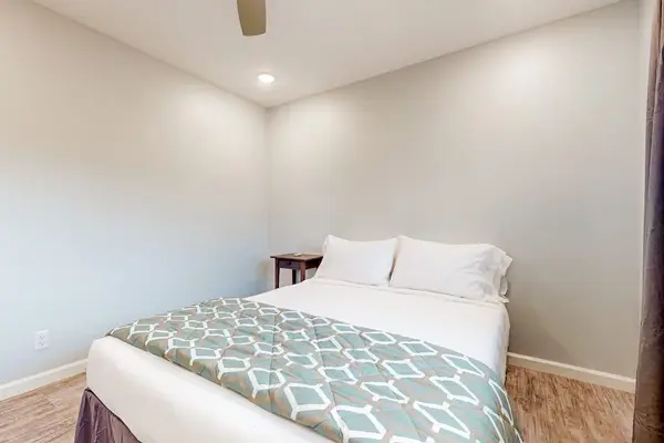 Guest room with queen bedroom with large windows.