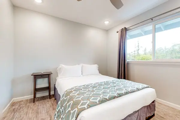 Guest room with queen bed and large windows.