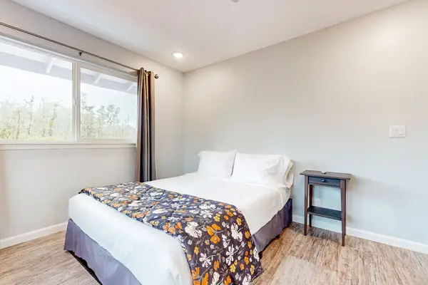 Guest room with queen bed and large picture windows.