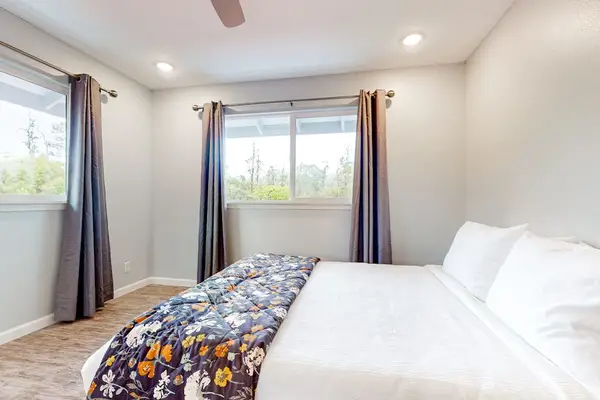 Guest room with queen bed and lots of natural light from multiple windows.