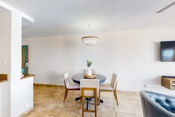 Dining area featuring a dark circular table paired with light-colored chairs in a bright room.