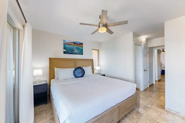 Bedroom with a wicker headboard, a ceiling fan, and a balcony overlooking the water.