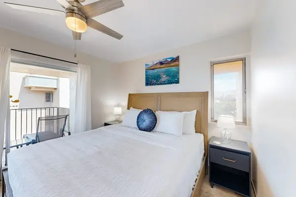 Bedroom with a wicker headboard, a ceiling fan, and a balcony overlooking the water.