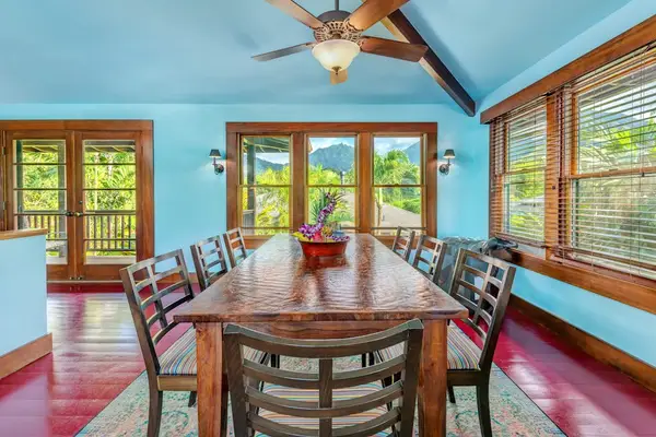 Dining room presents a wooden table surrounded by tropical views