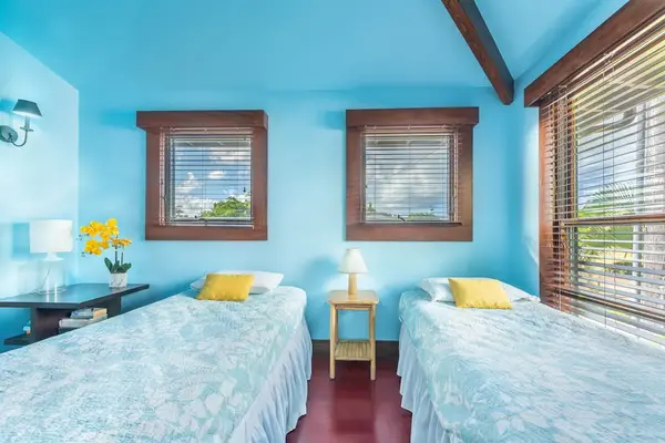 Modern bedroom features twin beds, fresh linens, and garden views