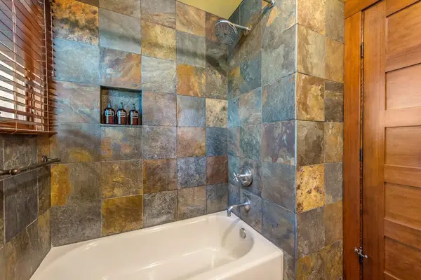 Modern bathroom showcases stone tilework, wooden cabinetry, and polished fixtures