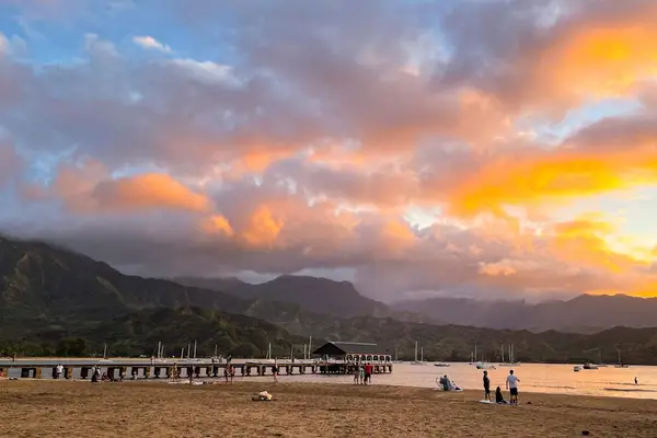 Beach sunset illuminates the shoreline with clouds and calm waters