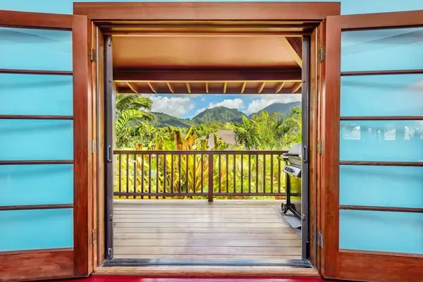 Wooden entryway opens toward lush tropical gardens and mountain views