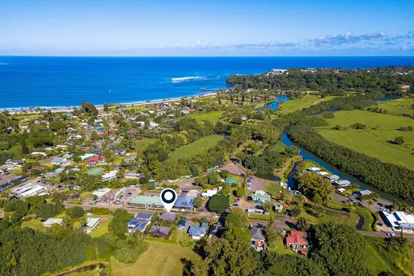 Aerial neighborhood view reveals coastal homes, fields, and distant ocean