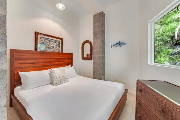 Sleek bedroom featuring a bold crimson headboard, towering ceilings, and a large picture window showcasing lush tropical views. 🌿✨