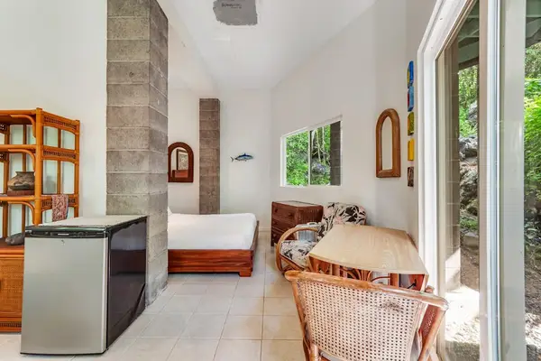 An architectural look at the guest retreat. Rich stone pillar textures, warm wood accents, and woven wicker seating contrast beautifully with a wall of glass looking out to the forest. 🌿🪨