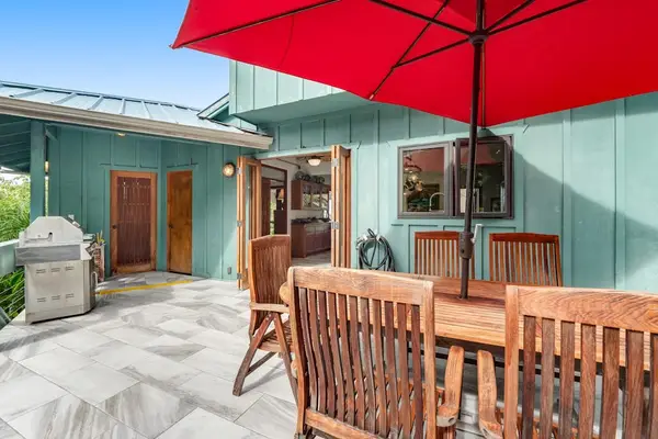 ​A detailed look at the stone-paved patio, featuring a dedicated outdoor dining set, rich wood tones, and a vibrant canopy designed for comfortable day-to-night lounging. ☂️🏡