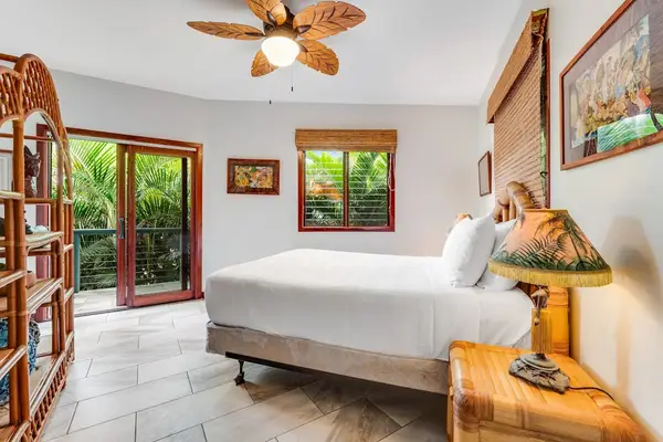 Wake up to nature! This bright bedroom features a plush bed, a cool ceiling fan, and direct sliding door access to a lush green outdoor area! 🛌🌀🌿