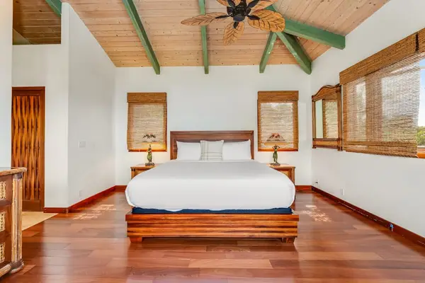 Rest in comfort! This expansive bedroom features gorgeous polished wood floors, rustic wood-paneled ceilings, and warm bedside lighting! 🛌🪵✨
