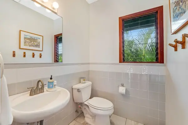 Crisp design meets natural warmth. This bright powder room pairs clean white finishes with a rich wood-framed window looking out to the lush foliage. 🌿🪟