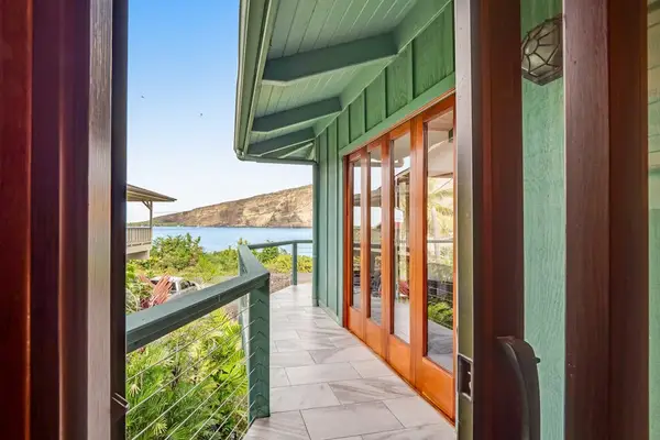 A study in structural lines. This perspective highlights a stunning run of warm wooden French doors set against a soft teal facade under deep, sheltering eaves. 📐🪵