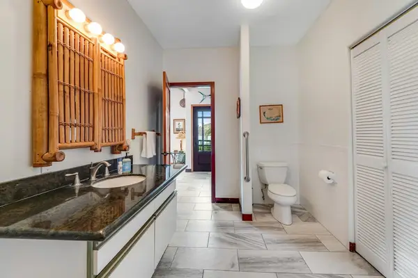 Fresh and clean! This bright bathroom features a spacious marble-top vanity, a large wood-framed mirror with warm lighting, and a modern layout! 🧼💡✨